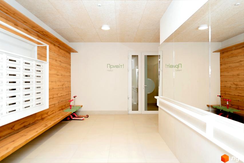 Сучасний вхід у житловий комплекс Долішній з поштовими скриньками та лавкою. На стіні напис 