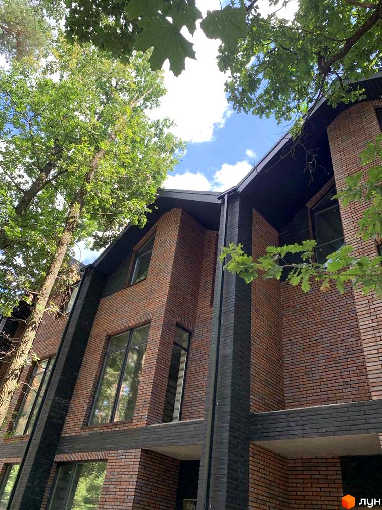 Таунхаус Forest Lane з цегляним фасадом та великими вікнами, оточений зеленню дерев.