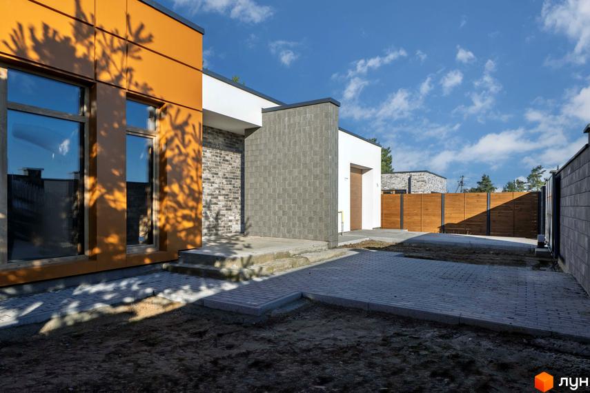 Котеджне містечко LOTUS. Зовнішній вигляд будинку з оранжевими та сірими елементами, вікнами та дерев'яним парканом.