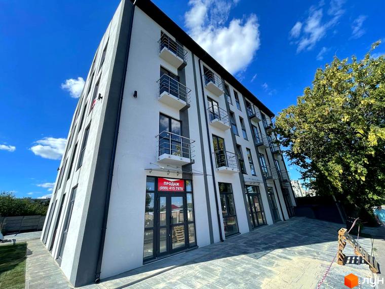 Новобудова Успішний квартал 2 з балконами та дверима на першому поверсі, поруч дерево та вимощена територія.