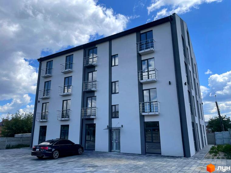 Зовнішній вигляд новобудови ЖК Успішний квартал 2 з балконами та вікнами, прибудинкова територія з автомобілем та бруківкою.