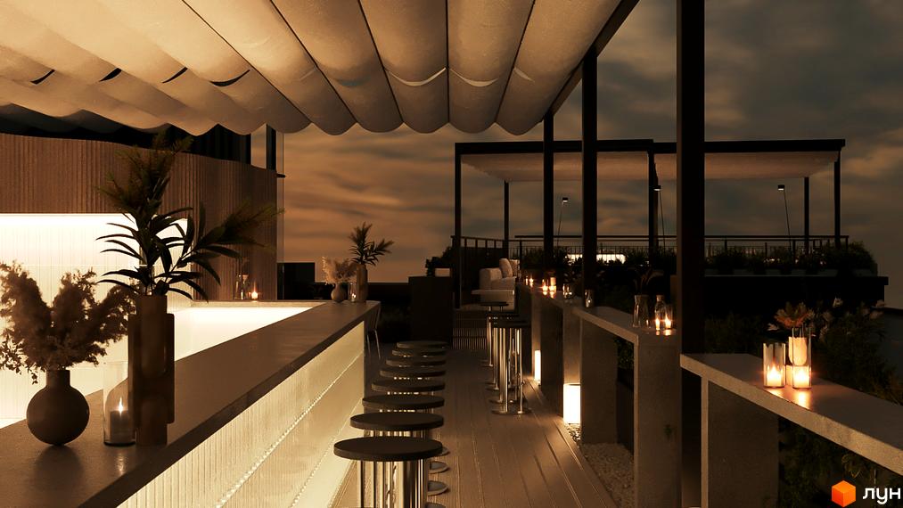 Тераса з баром та барними стільцями на даху ввечері. Навколо свічки та рослини, що створюють затишну атмосферу.