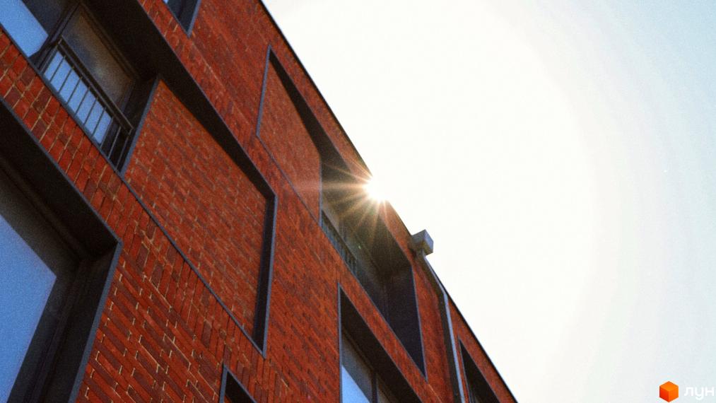 Фасад новобудови З.40 з червоної цегли та темними вікнами. Сонячний день, вид на архітектуру будинку.