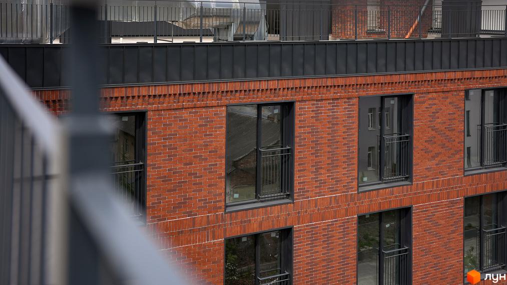 Фасад Житлового комплексу З.40 з червоної цегли, темними вікнами та невеликими балконами з металевими поручнями.