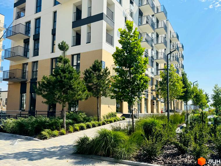 Житловий комплекс Садова Алея: фасади будівель з балконами та цегляною обробкою, зелена прибудинкова територія з деревами та доріжками.