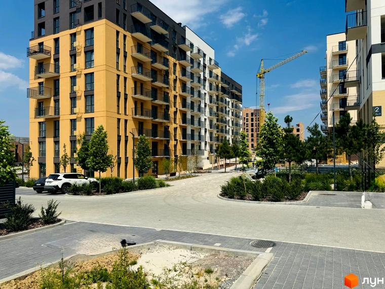 Житловий комплекс Садова Алея: жовті та білі новобудови з балконами, зелена прибудинкова територія з деревами та доріжками.