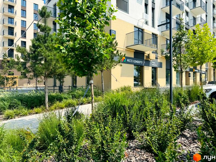 Житловий комплекс Садова Алея: фасади будівель з балконами та зелена прибудинкова територія з деревами та кущами.