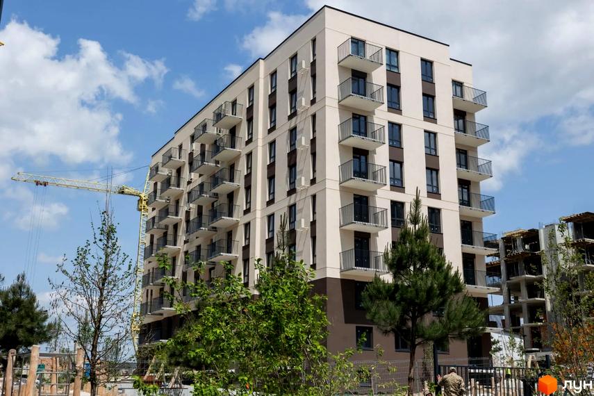 Житловий комплекс Садова Алея - сучасна багатоповерхова будівля з балконами та прибудинковою територією з деревами та будівельним краном.