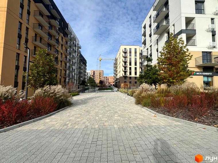 Житловий комплекс Садова Алея: сучасні будинки з балконами та доглянута прибудинкова територія з деревами та кущами.