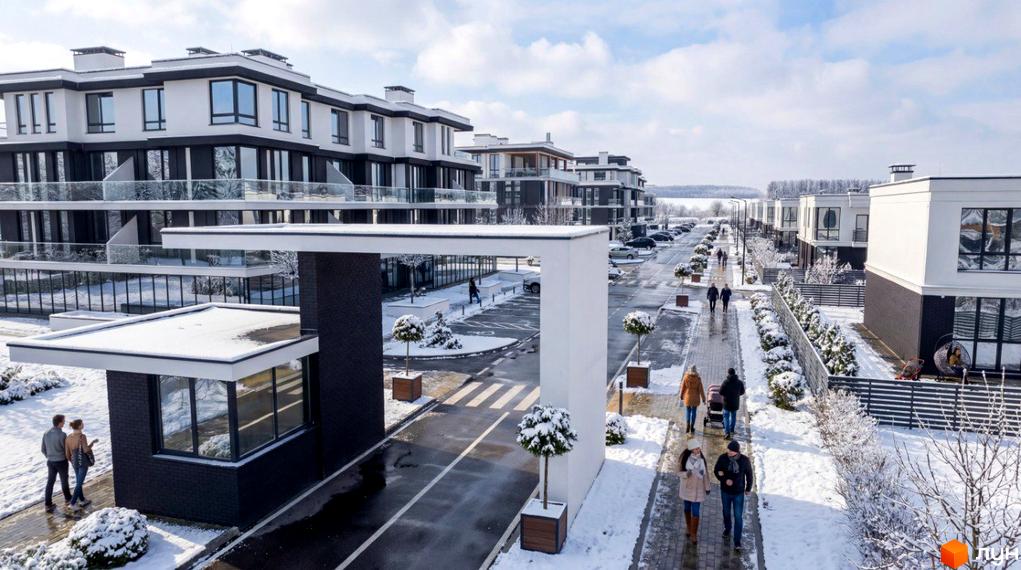 Котеджне містечко ParkWill: білі будинки з чорними елементами та скляними балконами, прибудинкова територія вкрита снігом, алея з деревами та людьми.