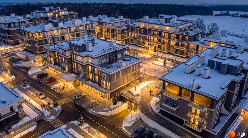 Котеджне містечко ParkWill: будинки з темними фасадами та світлими дахами в зимовий вечір. Освітлена територія зі снігом, дорогами та парковками.