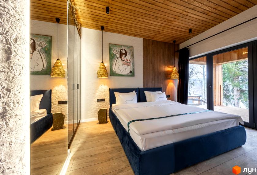 Затишна спальня в котеджному містечку КМ Agat Resort & SPA з дерев'яною стелею та панорамним вікном на ліс. Інтер'єр виконаний в еко-стилі з натуральних матеріалів.