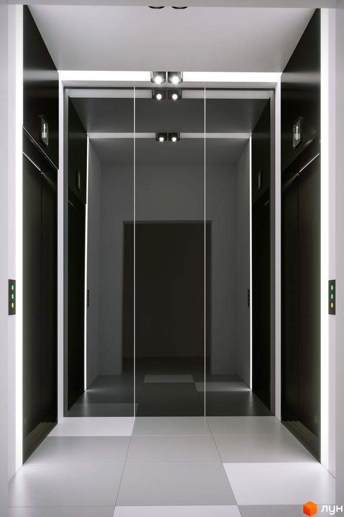 Сучасний вхід у новобудову Прохоровський квартал з темними ліфтовими дверима та скляним тамбуром. Освітлений коридор веде до ліфтів.