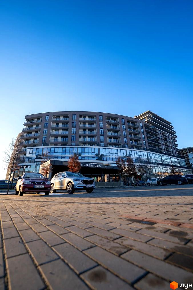 Зовнішній вигляд житлового комплексу Crystal з багатоповерховими квартирами та балконами, прибудинкова територія з паркуванням та бруківкою.