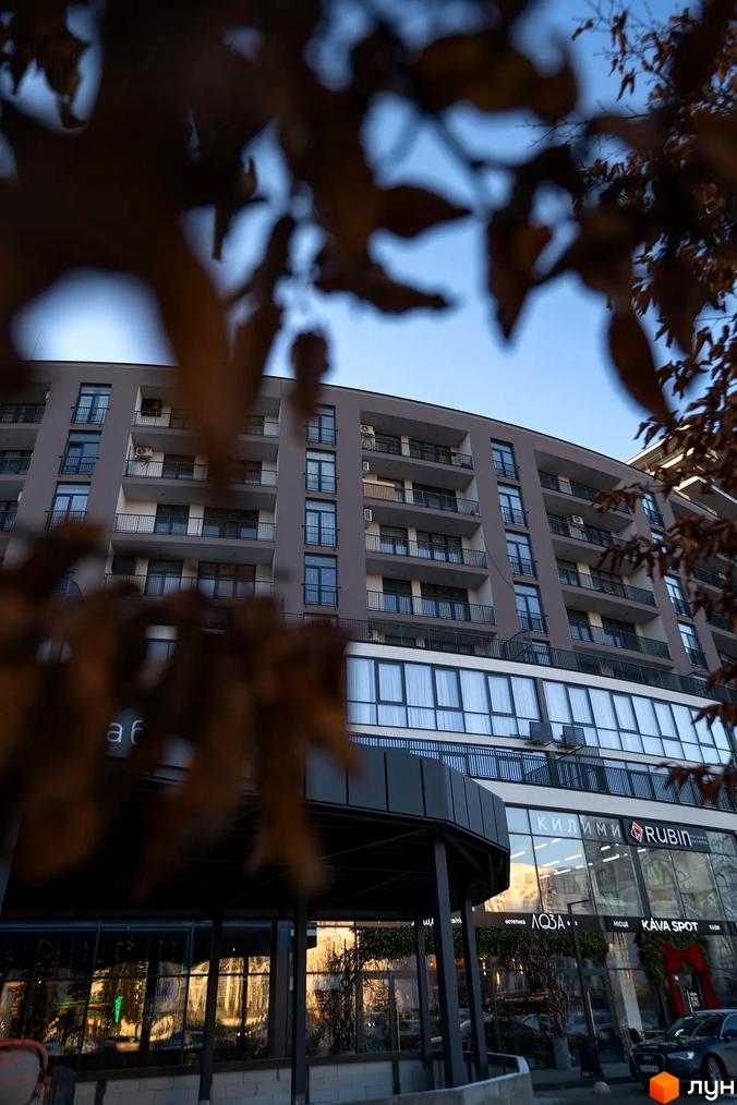 Житловий комплекс Crystal - багатоповерховий будинок з балконами та панорамними вікнами, поруч розташовані комерційні приміщення.