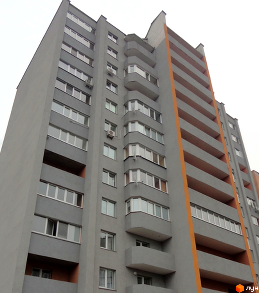Зовнішній вигляд багатоповерхового будинку ЖК Припортовий з сірими стінами та помаранчевими елементами. Вікна та балкони розташовані рядами.