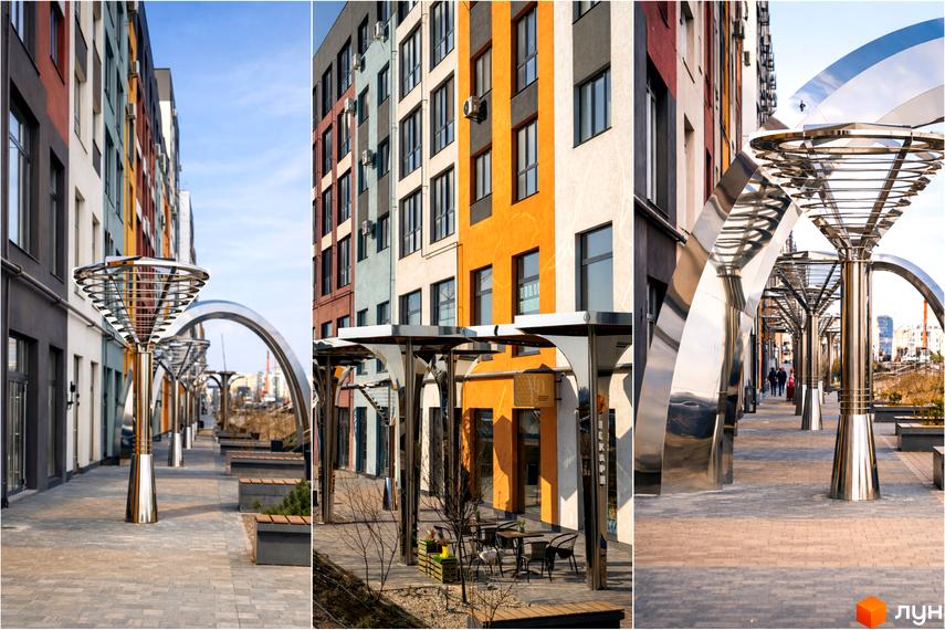 Житловий комплекс На Щасливому: фасади будинків з різнокольоровими елементами та доглянута прибудинкова територія з арками та лавками.