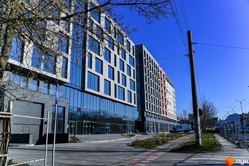 Новобудова ЖК Mill Town з панорамними вікнами та сірими фасадами. Поруч дорога та зелена зона.