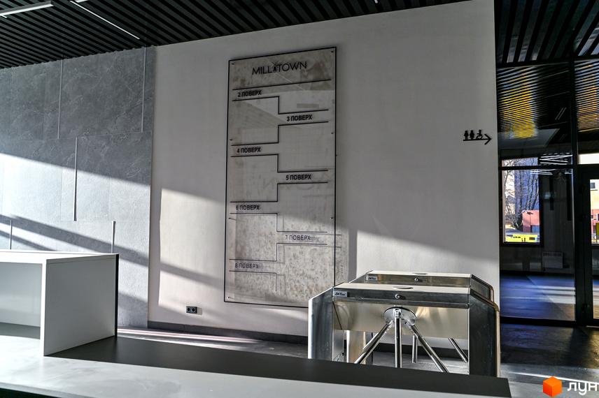 Вхідна група та навігаційна таблиця поверхів у житловому комплексі Mill Town. Сучасний дизайн інтер'єру з акцентом на функціональність.