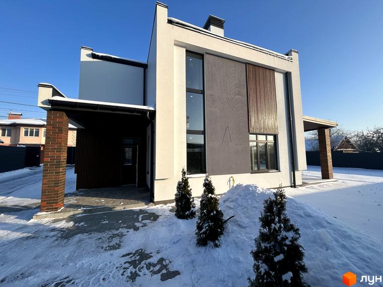 Двоповерховий будинок Котеджного містечка Будинки на Франка зі світлим фасадом та коричневими акцентами. Прибудинкова територія вкрита снігом з хвойними деревами.