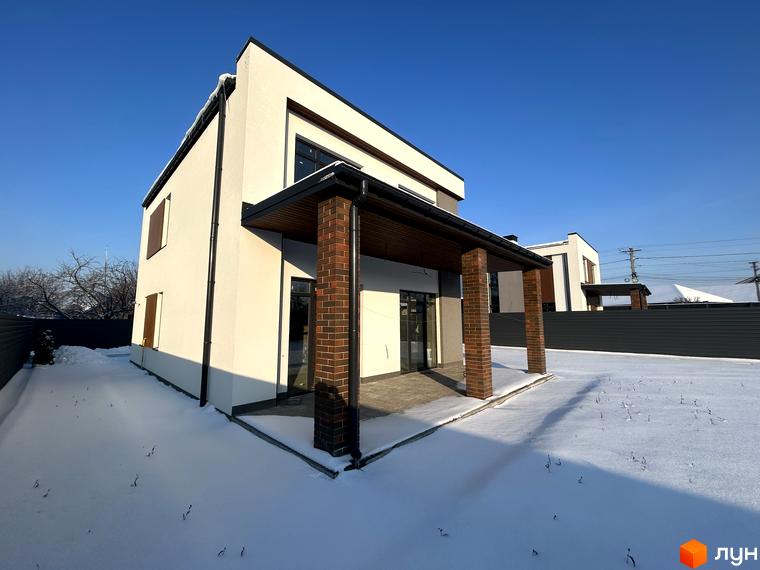 Котеджне містечко Будинки на Франка: двоповерховий будинок з цегляними колонами та навісом, оточений снігом. Навколо огороджена територія та сусідні новобудови.