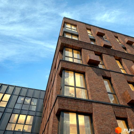 MOVIN hotel - це житловий комплекс з цегляним фасадом та великими вікнами, що відбивають небо. Поруч розташована будівля зі скляним дахом.