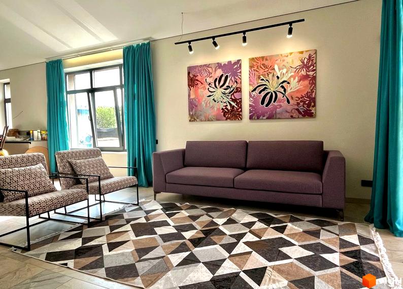 Інтер'єр вітальні в житловому комплексі КМ TAO Residence з диваном, кріслами та килимом з геометричним візерунком.