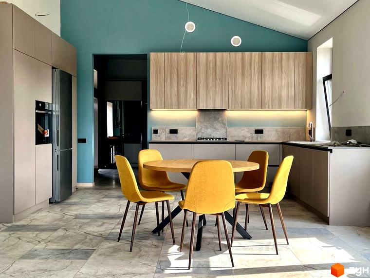 Інтер'єр кухні-вітальні з круглим столом та жовтими стільцями в КМ TAO Residence. Сучасна кухня з дерев'яними фасадами та бірюзовою стіною.