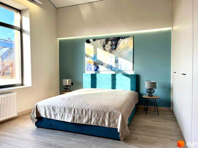 Спальня в Котеджному містечку TAO Residence з великим вікном, ліжком з бірюзовим узголів'ям та абстрактною картиною. Світлі стіни та дерев'яна підлога.