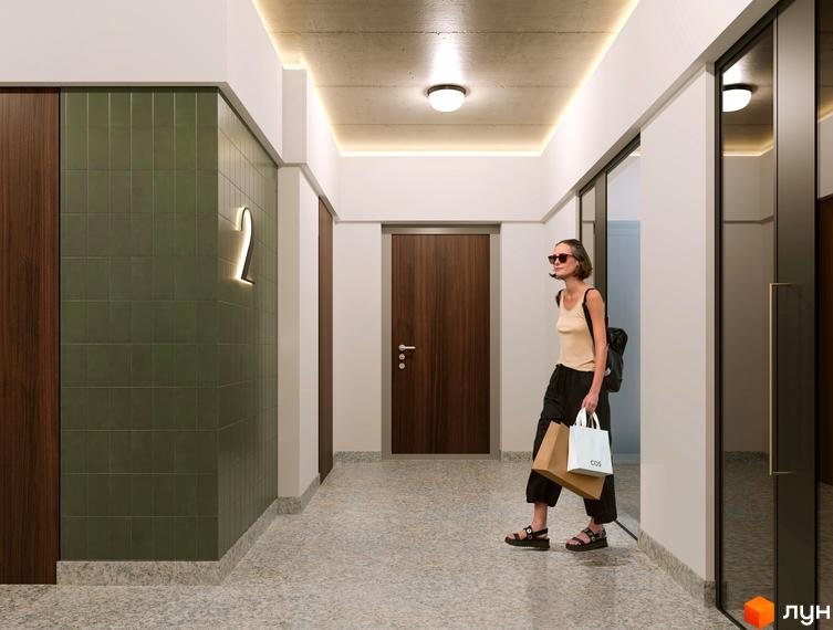Сучасний інтер'єр холу новобудови ЖК Слобідська з дверима та оздобленням стін. Жінка з сумками входить до будівлі.
