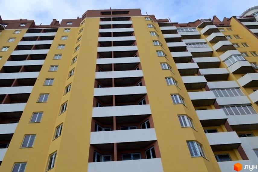 Висотна будівля ЖБК Левітана з балконами та вікнами. Житловий комплекс пофарбовано в жовтий колір з білими та коричневими елементами.