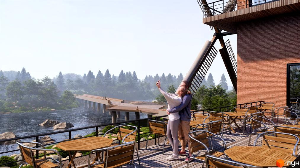 Котеджне містечко КМ PAZZA Village and Spa з цегляним фасадом та терасою біля річки з видом на міст та ліс.