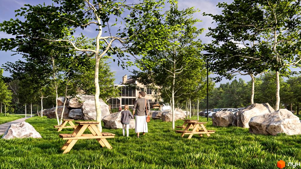 Котеджне містечко КМ ПАВЗА Village and Spa з парковою зоною, пікніковими зонами та великими валунами. На задньому плані видно будівлю комплексу та парковку.