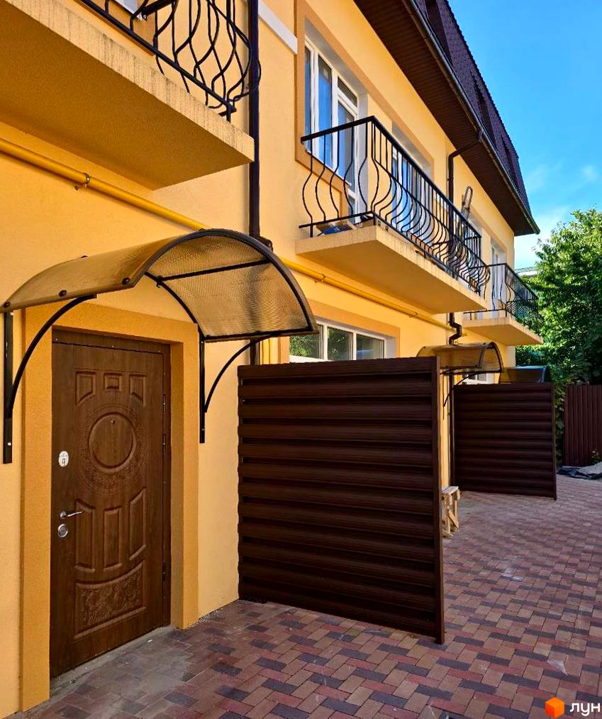 Зовнішній вигляд таунхаусів Родинний Преміум 2 з індивідуальними входами та огородженою прибудинковою територією. Фасад будинку виконаний у жовтому кольорі, балконні огородження ковані.