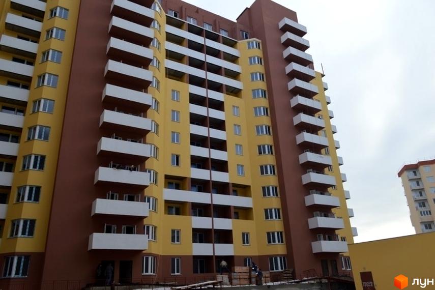 Висотна новобудова ЖБК Левітана з жовтим фасадом та білими балконами. На прибудинковій території видно будівельні роботи та парковку.
