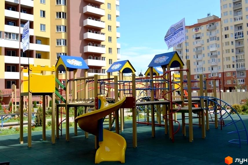 Житловий комплекс Левітана з дитячим майданчиком. Житловий комплекс розташований біля багатоповерхових будинків з балконами.