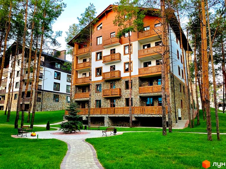 Житловий комплекс DESNA residence - багатоповерхові будинки з дерев'яними балконами та кам'яним оздобленням на тлі соснового лісу. Прибудинкова територія з доглянутим газоном та доріжками.