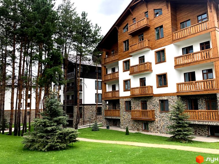 Житловий комплекс DESNA residence з дерев'яними фасадами та балконами, оточений соснами та доглянутим газоном. Зовнішній вигляд новобудови.