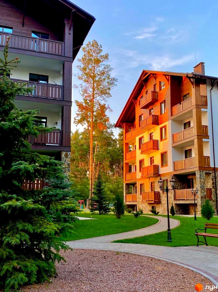 Житловий комплекс DESNA residence з дерев'яними фасадами та балконами, оточений зеленою територією з доріжками та лавками.