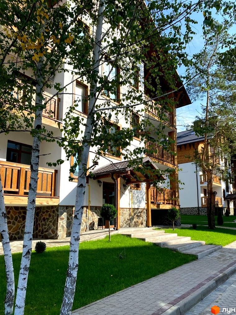 Будівельний проєкт DESNA residence з дерев'яними балконами та фасадами, оточений зеленою прибудинковою територією з доріжками та газонами.