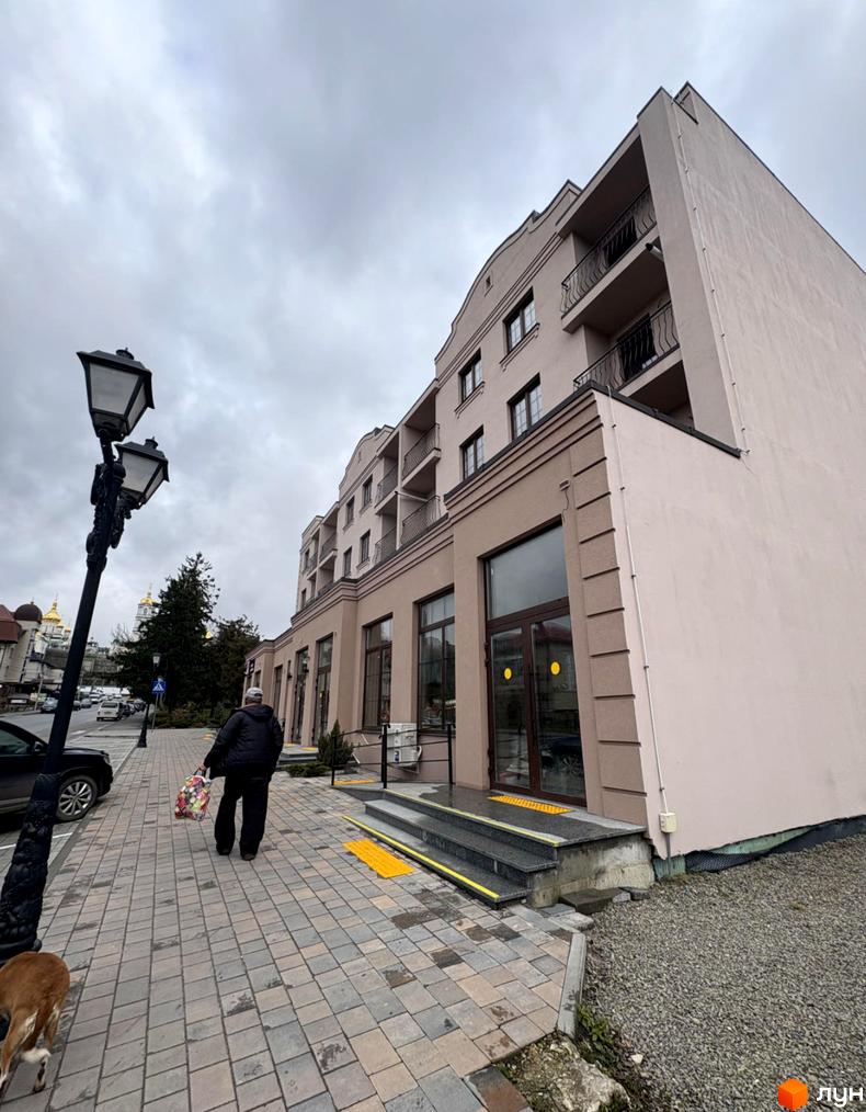 Зовнішній вигляд новобудови на вул. Лосятинська, 1а, з бруківкою та ліхтарем на прибудинковій території.