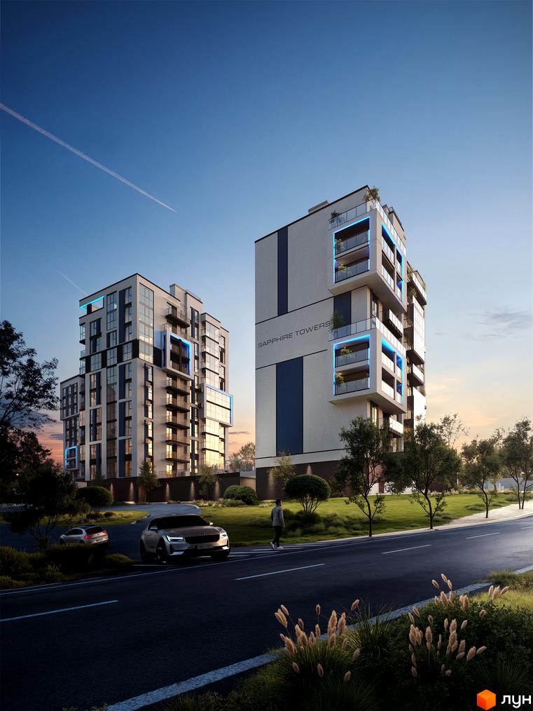 Житловий комплекс Sapphire Towers з скляними балконами та блакитною підсвіткою на тлі неба. Навколо будівлі зелена територія та дорога з автомобілями.