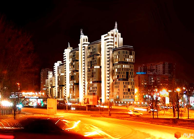 Житловий комплекс Павловський квартал вночі. Багатоповерхові будинки з підсвіченими вікнами та фасадами, розташовані біля дороги з яскравим освітленням.