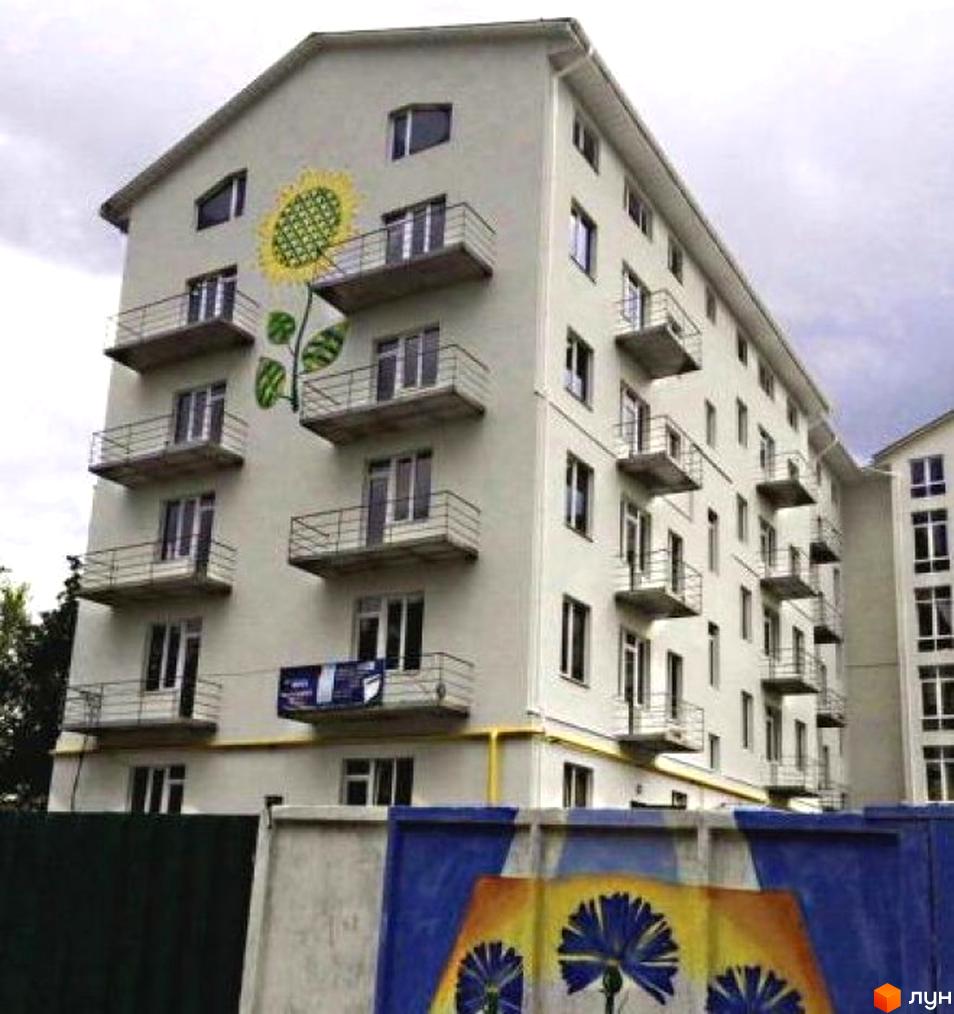Фасад житлового комплексу на вул. Дизельна, 14 з великою фрескою соняшника. Будинок має балкони та вікна, а перед ним розташована огорожа з муралом.