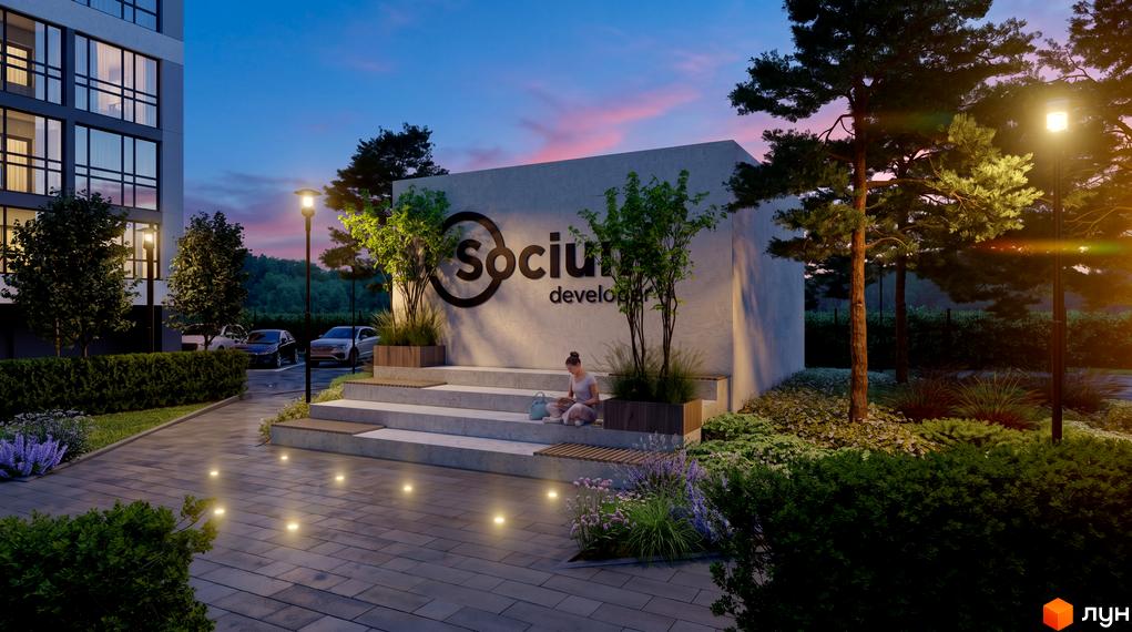 Зовнішній вигляд новобудови Socium developer з підсвіченою вивіскою та прибудинковою територією з деревами та лавочками.