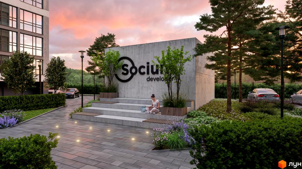 Зовнішній вигляд новобудови Socium developer з бетонною стіною та логотипом, зеленою прибудинковою територією та місцями для відпочинку.