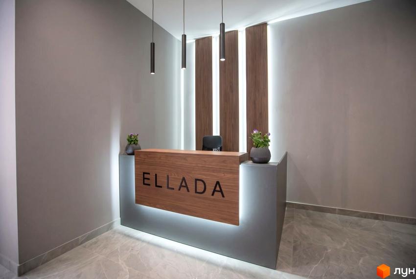 Рецепція Житлового комплексу Еллада з дерев'яною стійкою, написом ELLADA, підсвічуванням, декоративними панелями та підвісними світильниками.