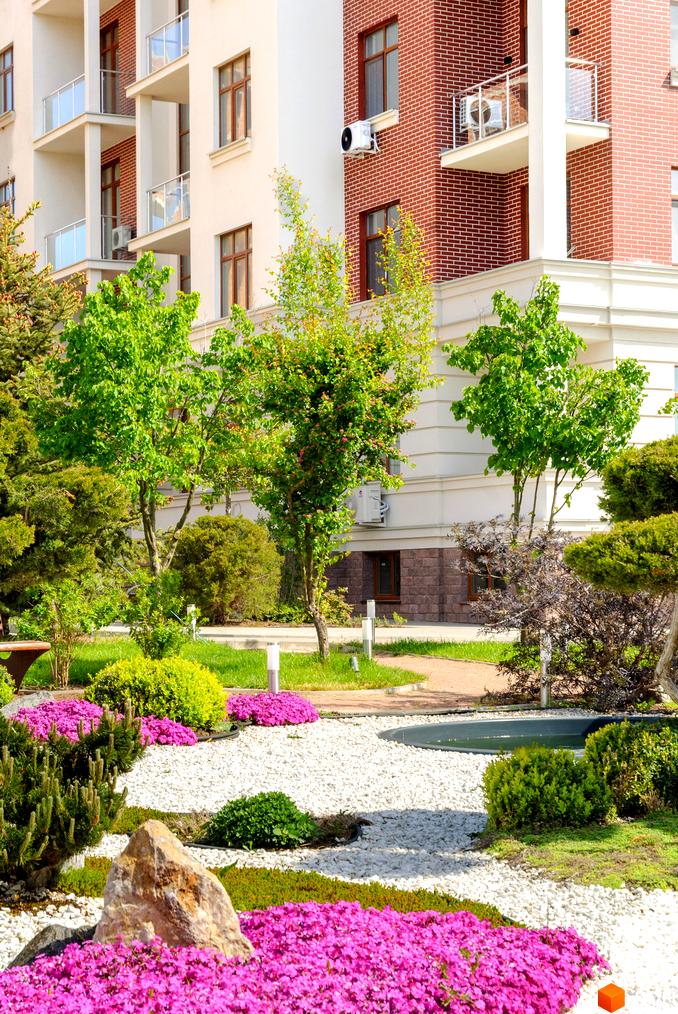 Житловий комплекс Парк Совіньйон: цегляні та білі фасади будівель з балконами, доглянута прибудинкова територія з квітами та деревами.