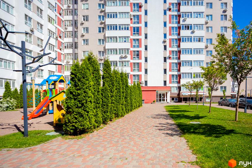 Житловий комплекс Сакура: фасади будинків з червоними та білими акцентами, дитячий майданчик та зелена зона.