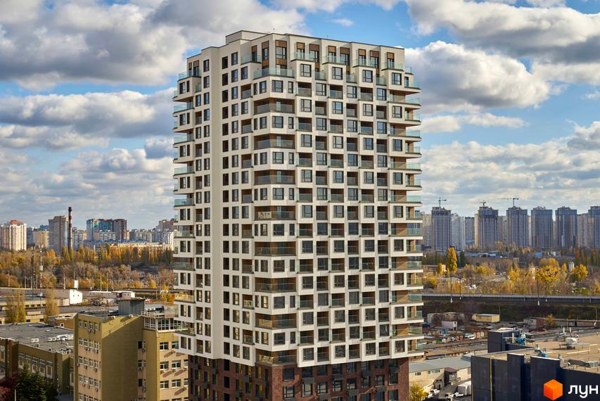 Багатоповерховий житловий комплекс Kub29 зі світлим фасадом, квадратними вікнами та скляними балконами на тлі міського ландшафту з осінніми деревами.